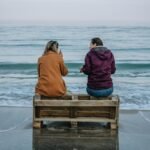 Two women sitting on a pallet by the Odesa shoreline, enjoying the serene sea view.