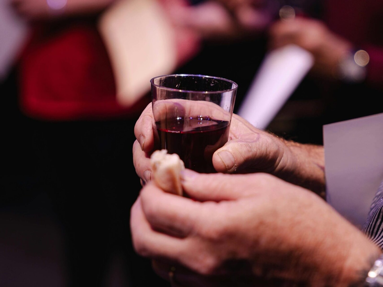 Intimate capture of communion ritual with bread and wine, indoors setting.